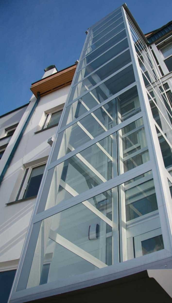 Buitenlift met glazen schacht tegen de gevel van een appartementencomplex